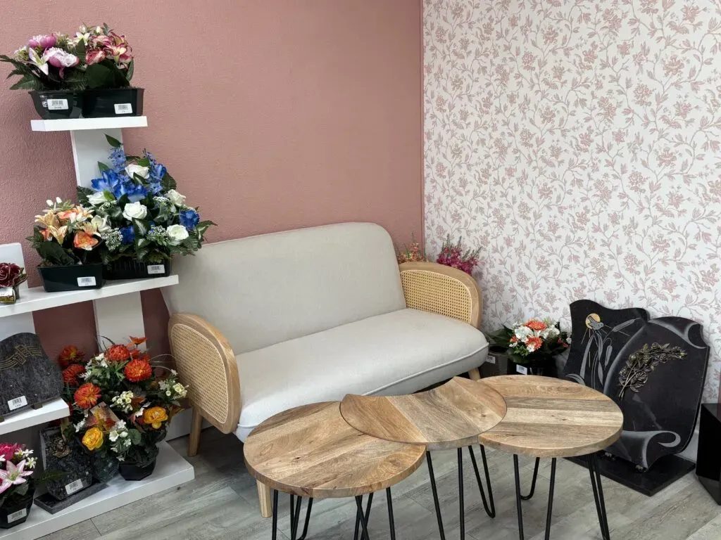 Espace d'accueil chaleureux avec canapé et tables basses dans une agence funéraire.