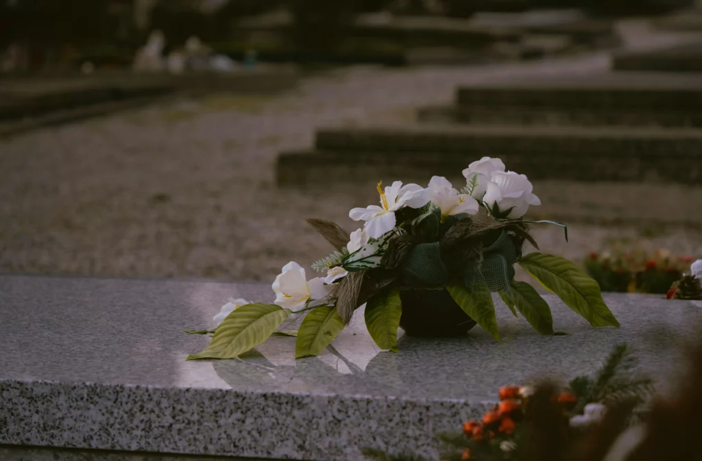 Arrangement de fleurs blanches posé sur une pierre tombale en marbre au cimetière.