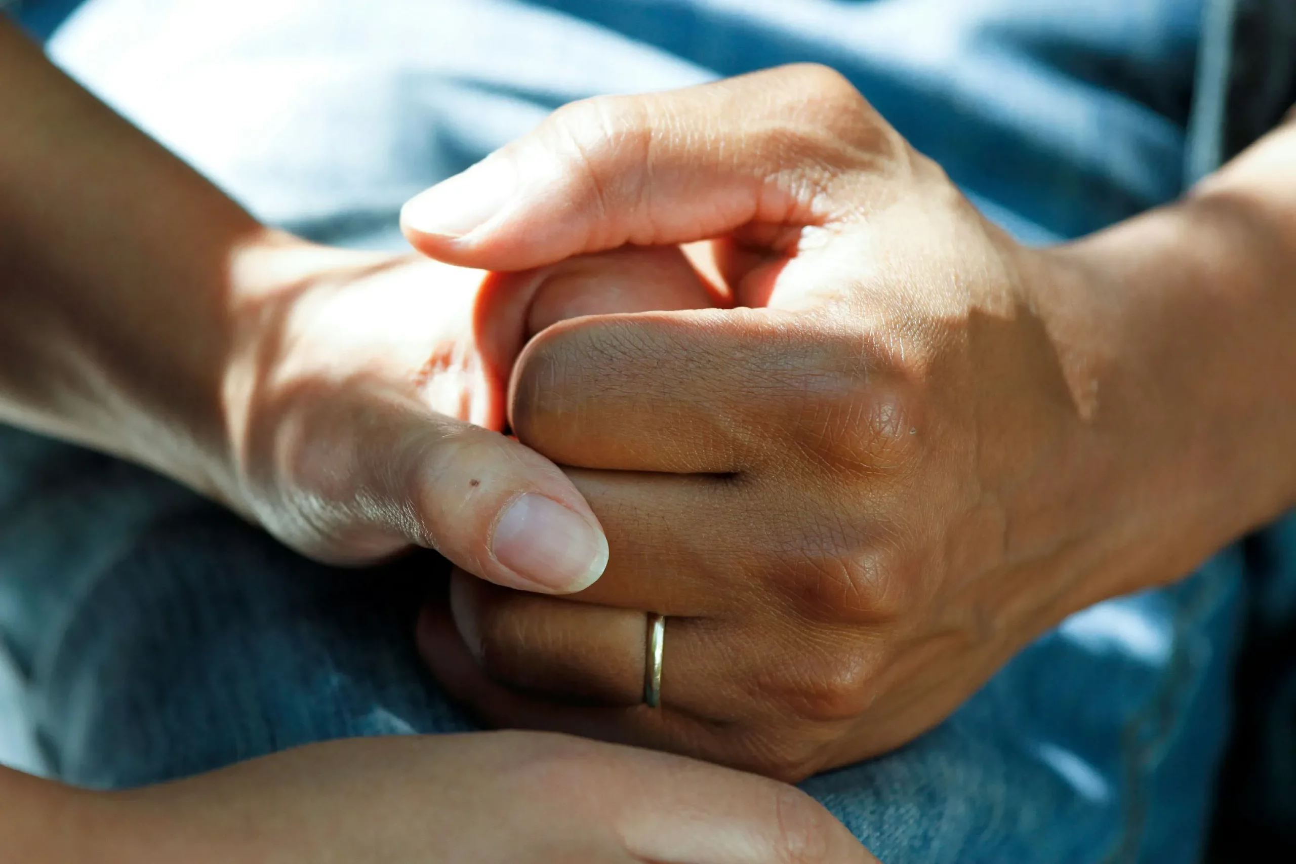 Gros plan de deux mains qui se serrent avec réconfort et empathie lors d'un deuil.